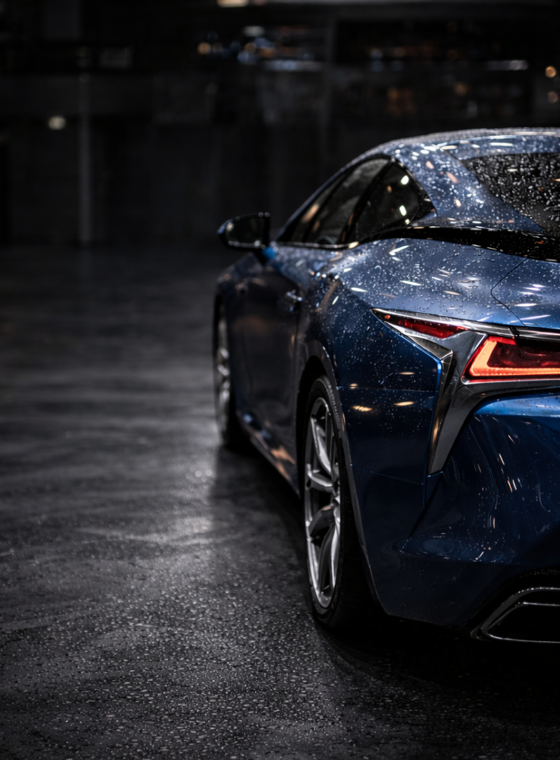 Starker Wasserabperleffekt auf dem tiefblauen Lack eines Sportwagens nach dem Auftrag einer professionellen Fahrzeug-Versiegelung