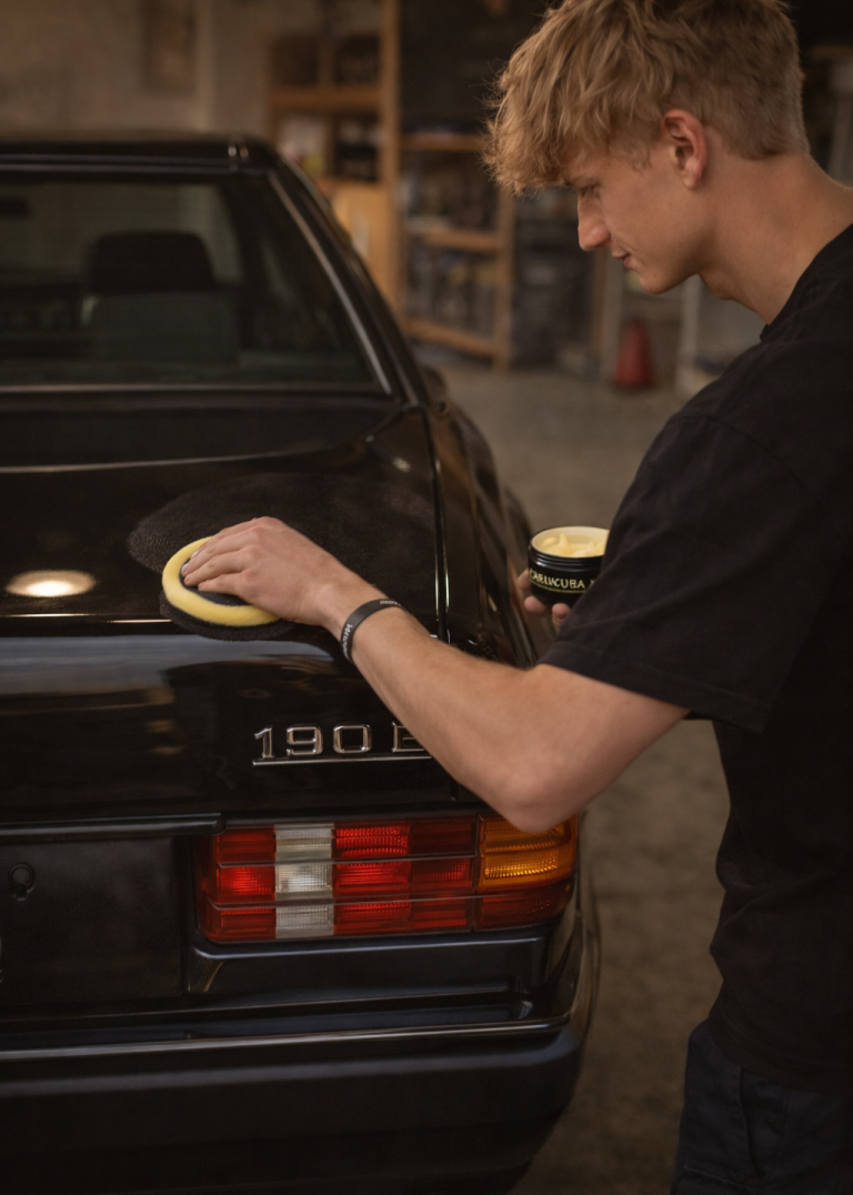 Hochwertiger Wachsschutz für den Mercedes 190E Handauftrag von hochwertigem Schutzwachs mit einem Pad auf den schwarzen Lack eines Mercedes 190E Oldtimers.